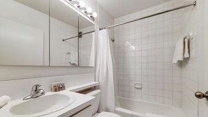 A modern bathroom with a white sink, mirror, and shower curtain. - Upscale Living | Midtown West |  Doorman & Rooftop (New York)