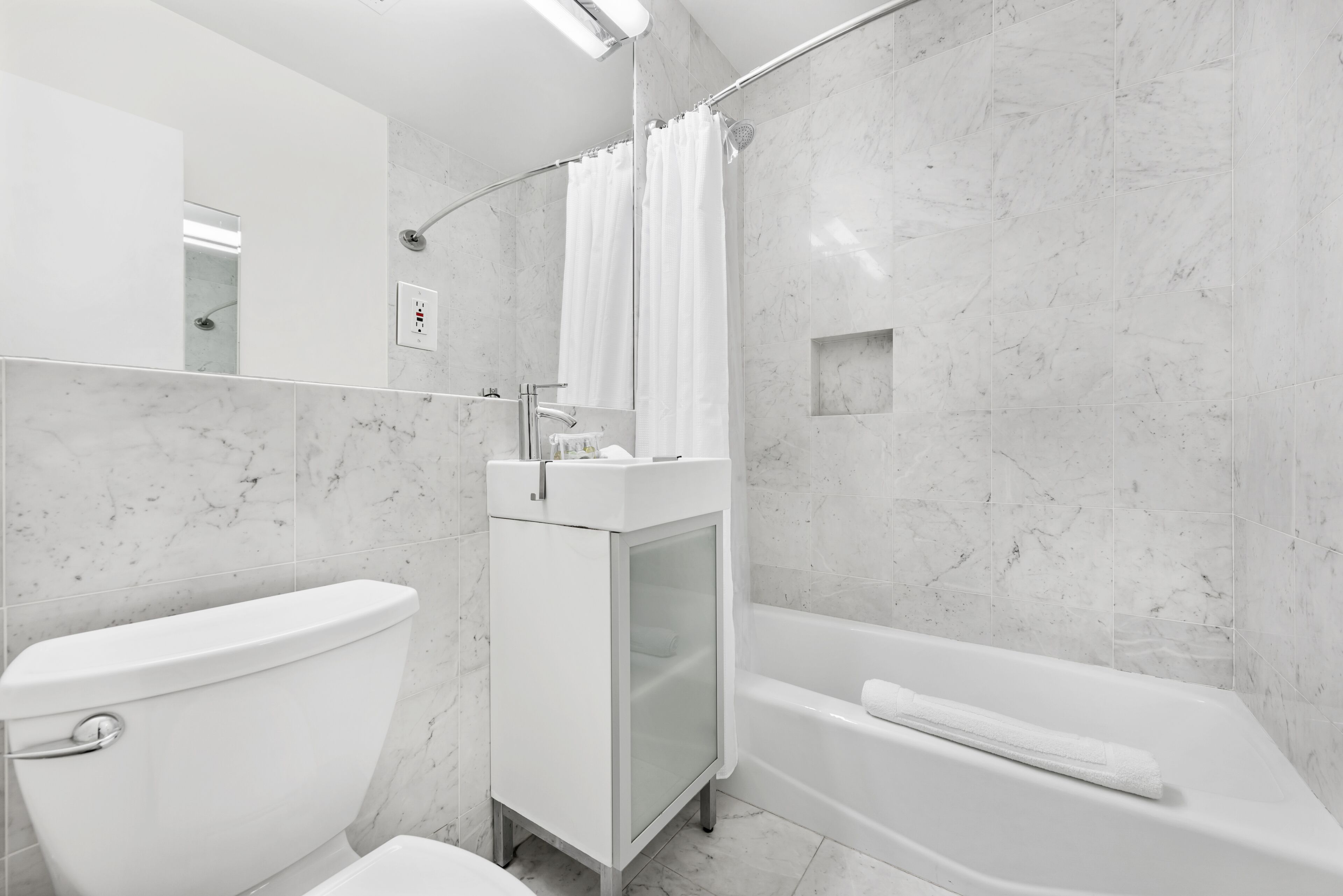 Un baño moderno con inodoro, lavamanos con cristal y bañera.