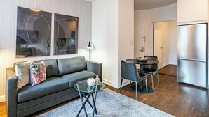 Een moderne woonkamer met een bank, een glazen salontafel en een eethoek met stoelen en een tafel.