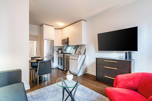 Ein modernes Wohnzimmer mit einem roten Sofa, einem Glastisch und einem an der Wand befestigten Flachbildfernseher.