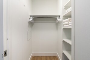 A walk-in closet with a wooden floor, white walls, and shelves on the right. - Stunning Greenwich Village Studio with Amenities (New York)