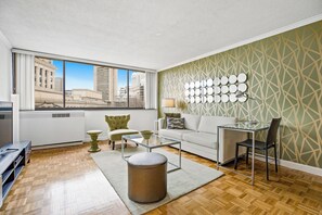 A modern living room with a large window, a glass coffee table, a white sofa, and a patterned wall. - 1 Bedroom in Back Bay, Boston's Best Neighborhood (Boston)