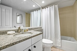 Un baño con lavamanos, espejo e inodoro blancos.