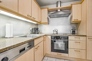 A modern kitchen with wooden cabinets, a stainless steel range hood, a coffee maker, and a dishwasher. - 1 Bedroom in Back Bay, Boston's Best Neighborhood (Boston)