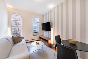 Un salon moderne comprenant un canapé, une table basse, un téléviseur et un coin repas.