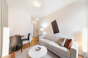 A modern living room with a sofa, a coffee table, and a dining area with chairs.