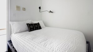 A bedroom with a bed, white bedding, a black lamp, and a window. - UES Escape | Marble Finishes, Elevator (New York)