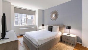 Ein modernes Schlafzimmer mit einem großen Bett, Nachttischen, einem Spiegel und Blick auf die Stadt durch das Fenster.
