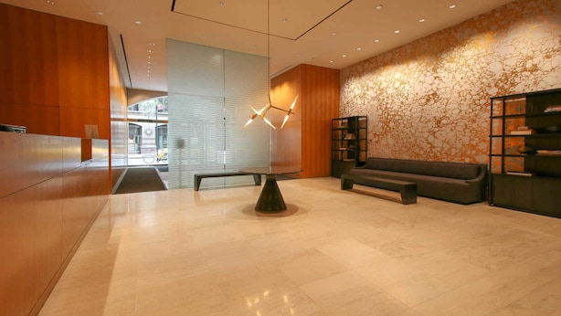 Eine moderne Lobby mit einem Holzbüro, einem runden Tisch, einer Couch und einem Bücherregal.