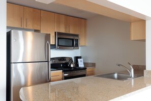 Una cocina moderna con electrodomésticos de acero inoxidable, armarios de madera y encimera de granito.