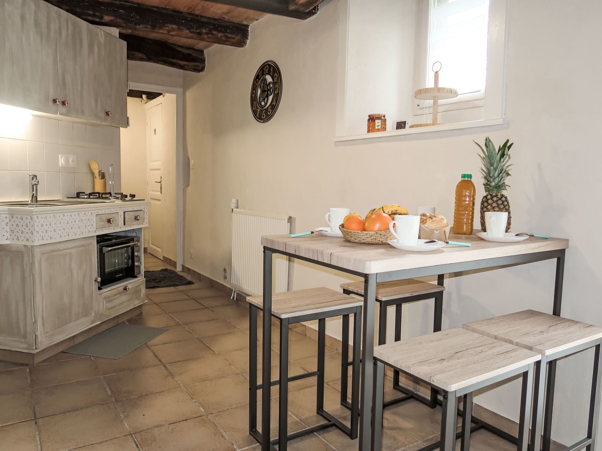 Una cucina moderna con zona pranzo, che include un tavolo in legno, sedie e un cesto di frutta.