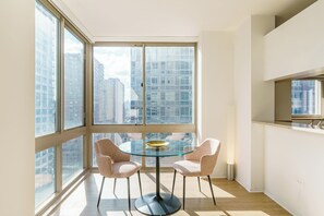 Una habitación moderna con ventanas amplias, una mesa redonda de cristal y dos sillas.