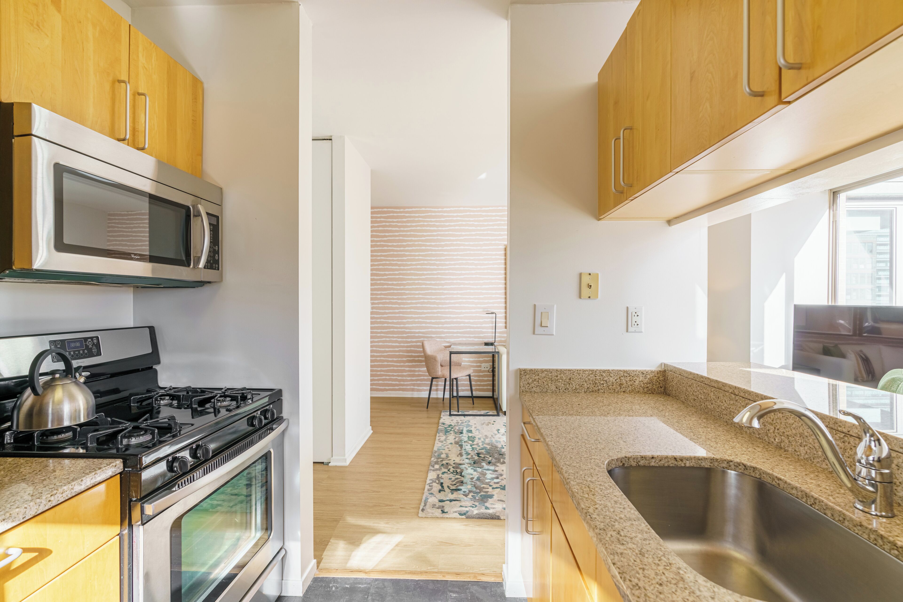 A kitchen with wooden cabinets, a stainless steel sink, a microwave, and a stove.