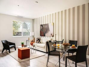 A modern living room with a glass dining table, a sofa, and a coffee table. - Modern One Bedroom in Silicon Valley (Sunnyvale)