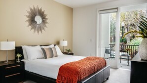 A modern bedroom with a large bed, two bedside tables, a decorative mirror, and a view of the outdoors through a sliding glass door. - Silicon Valley One Bedroom with Terrace (Sunnyvale)