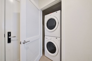 A laundry room with two stacked front-loading washing machines and a door with a modern lock.