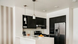 A modern kitchen with a central island, dark cabinetry, stainless steel appliances, and a striped wall pattern. - Silicon Valley One Bedroom with Terrace (Sunnyvale)