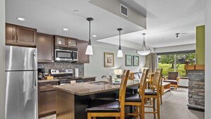 Una cocina moderna con encimeras de granito, electrodomésticos de acero inoxidable y sillas de madera.