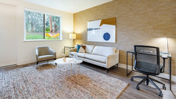 A modern living room with a sofa, armchair, coffee table, and office chair.