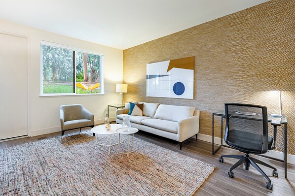 A modern living room with a sofa, armchair, coffee table, and office chair.