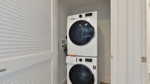Un cuarto de lavandería con dos lavadoras de carga frontal apiladas.