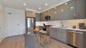 Una cocina moderna con electrodomésticos de acero inoxidable, una mesa de comedor de vidrio y armarios grises.