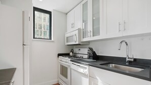 A modern kitchen with white cabinetry, a stainless steel sink, and a built-in microwave.