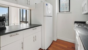 Eine moderne Küche mit weißen Schränken, einer schwarzen Arbeitsplatte, einem Edelstahlherd und einem Fenster mit Blick auf die Stadt.