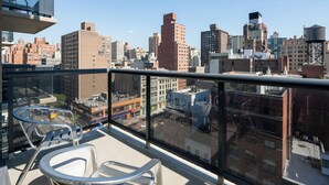 A balcony with a city view, metal chairs, and a glass railing. - Chic Gramercy Retreat | W/D, Rooftop Deck (New York)
