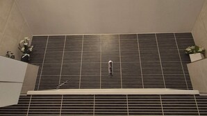 Een dakraam in een badkamer met een betegelde muur en ventilatie.