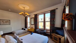 Een hotelkamer met twee bedden, een bureau, een stoel, een radiator, een kaart aan de muur en een raam met gordijnen.