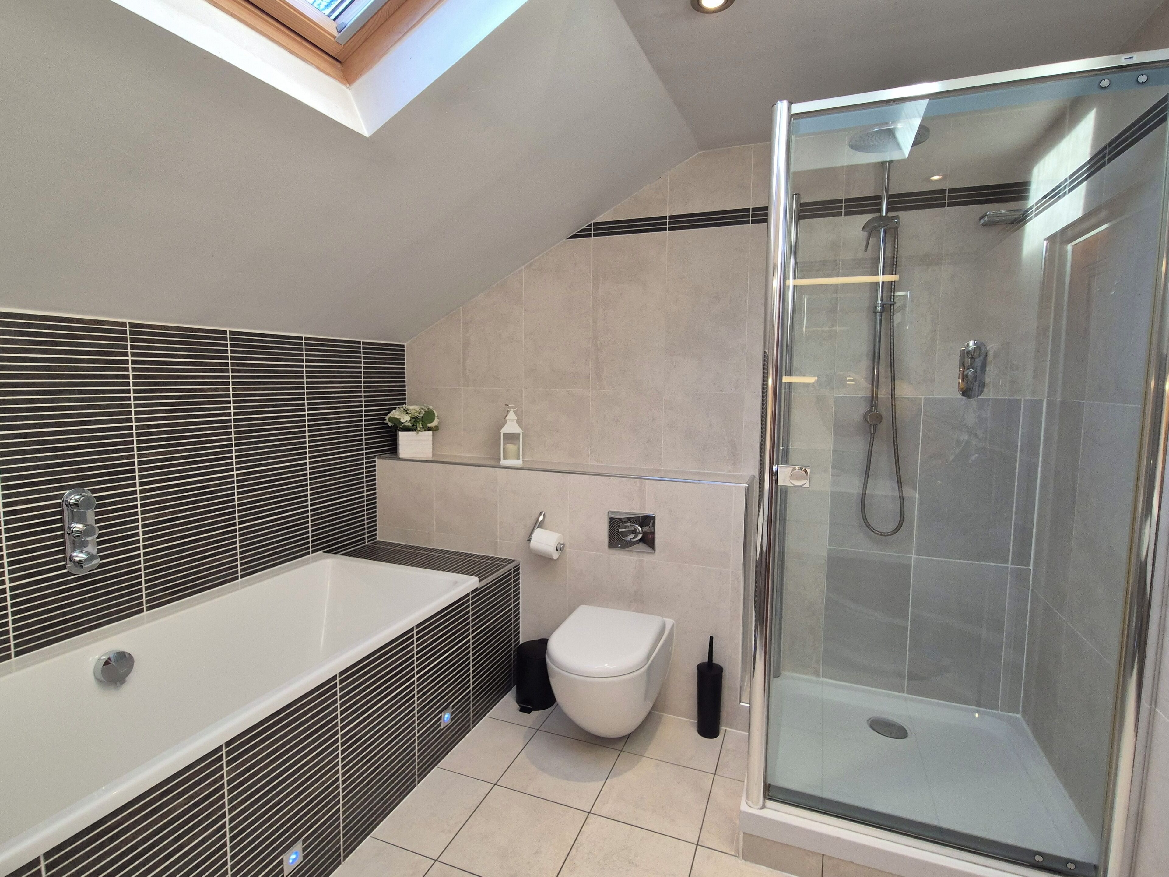 Et moderne badeværelse med et glasafskærmet brusebad, et fritstående badekar og et toilet.