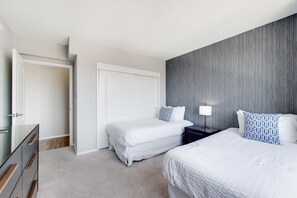 A bedroom with two beds, a dresser, a nightstand, and a door. - Modern 2 Bedroom in Central White Plains (White Plains)