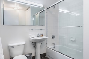 A modern bathroom with a toilet, sink, and glass-enclosed shower. - Bright Midtown West Living | W/D, Fitness Center (New York)
