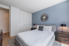 A bedroom with a bed, nightstands, a wardrobe, and a wall-mounted mirror.