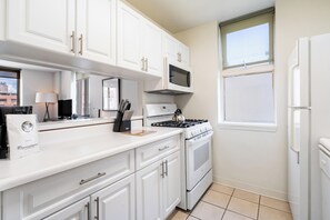 A modern kitchen with white cabinetry, a microwave, stove, oven, and a refrigerator. - Stay in the UES | Pet-Friendly, On-Site Laundry (New York)