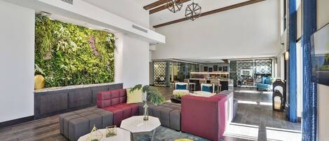 Un espace lounge moderne avec un mur végétal, des sièges et un bar en arrière-plan.