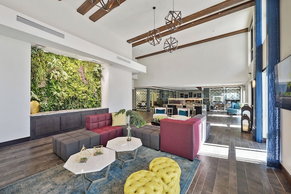 A modern lounge area with a green wall, seating, and a bar in the background.