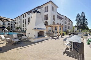 A poolside area with outdoor seating, a barbecue grill, and a pool.