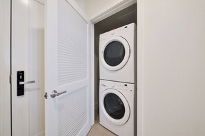 A laundry room with two stacked front-loading washing machines and a door with a modern lock.
