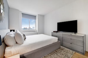 Quarto moderno com cama grande, televisão e vista para a cidade.