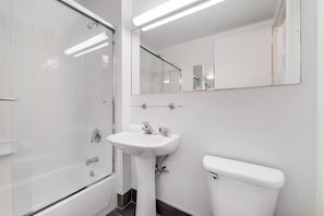 Um banheiro moderno com box de vidro, pia branca e vaso sanitário.
