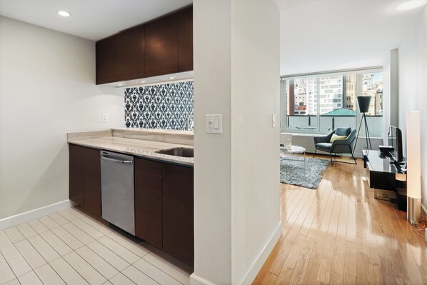 A modern kitchen with dark cabinets, a dishwasher, and a patterned backsplash.