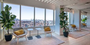 Ein modernes Interieur mit großen Fenstern, zwei Kübelpflanzen und Blick auf die Stadt.