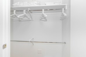 A white closet with a metal rod and plastic hangers. - 1 Bedroom near Rose Kennedy Greenway (Boston)