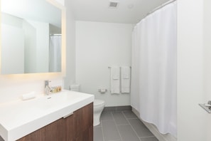 Casa de banho moderna com lavatório branco, espelho e sanita.