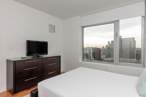 Une chambre à coucher avec un lit, une commode et un téléviseur.
