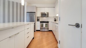 A modern kitchen with white cabinetry, stainless steel appliances, and a wooden floor. - Modern 1 Bedroom in Downtown Boston (Boston)