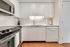 A modern kitchen with white cabinets, a stainless steel stove, a microwave, and a dishwasher. - Modern 1 Bedroom in Downtown Boston (Boston)