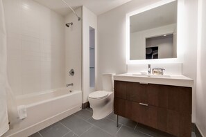 A modern bathroom with a bathtub, toilet, and vanity with a mirror.